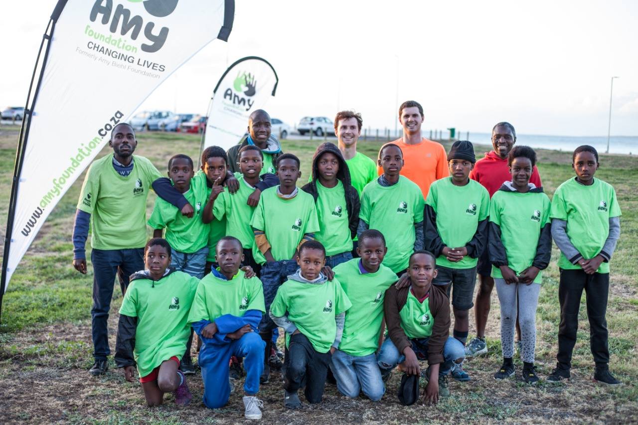 A group of young boys in bright green Amy Foundation shirts stand and kneel with five adults for a group photo